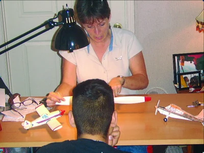 An aviation instructor communicates with her learner using model airplanes to ensure the learner's understanding of the principles discussed.